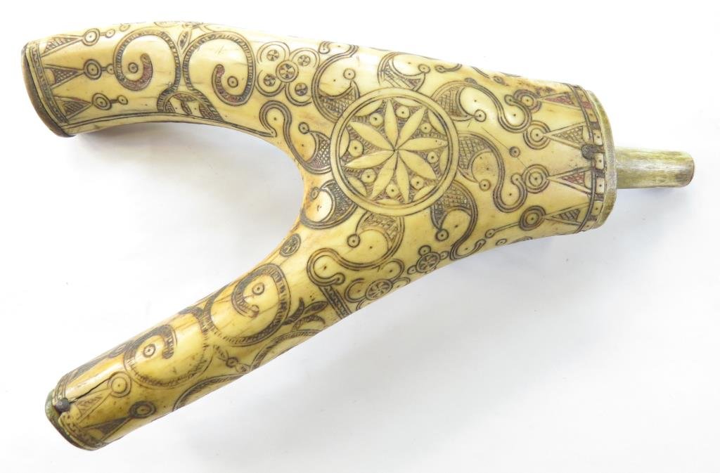 A RARE CARPATHIAN POWDERHORN: An exceptional example made from a large branch of staghorn, the obverse polished smooth and finely incised overall in complex geometrical and talismanic motifs. With separately-applied cap and spout,