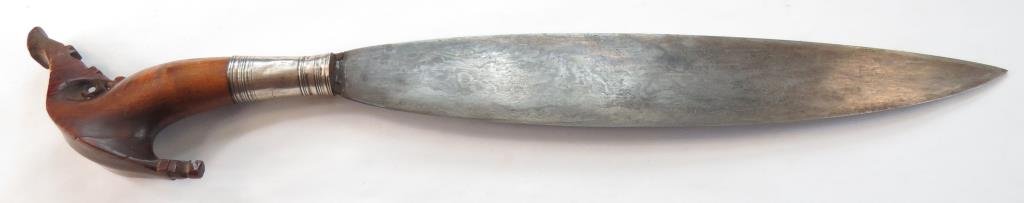 A MORO BARONG SHORTSWORD: The Tausug-style grip carved of banati wood with large kakatua pommel and silver ferrule. The handforged blade with fine and complex damascus steel pattern. Latter 19th century. Minor checking to grip