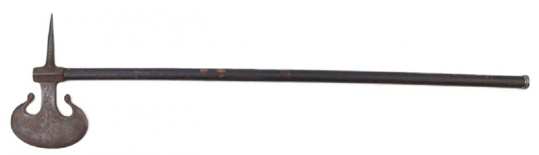 A PERSIAN BATTLEAXE: Qajar Dynasty, a rarely encountered type. The heavy crescent head engraved overall with animals among foliage and wrought with a long, armor-piercing backspike. On its hardwood haft with silver ferrul