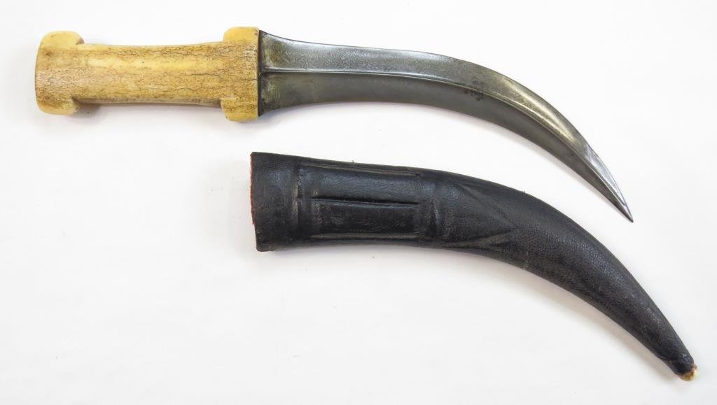 A PERSIAN KHANJAR DAGGER: The waisted walrus grip of characteristic form, the curved, double-edged blade forged of fine Persian black wootz steel with raised central ridge and armor-piercing tip. In its leather-covered wooden 