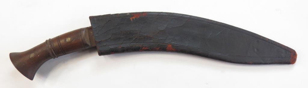 A MILITARY KUKRIE KNIFE: With wooden handle and bellied blade, struck1915 at the forte with additional illegible markings. Heavily stoned. In its original leather-covered wooden scabbard. Early 20th century. Worn. Overall len