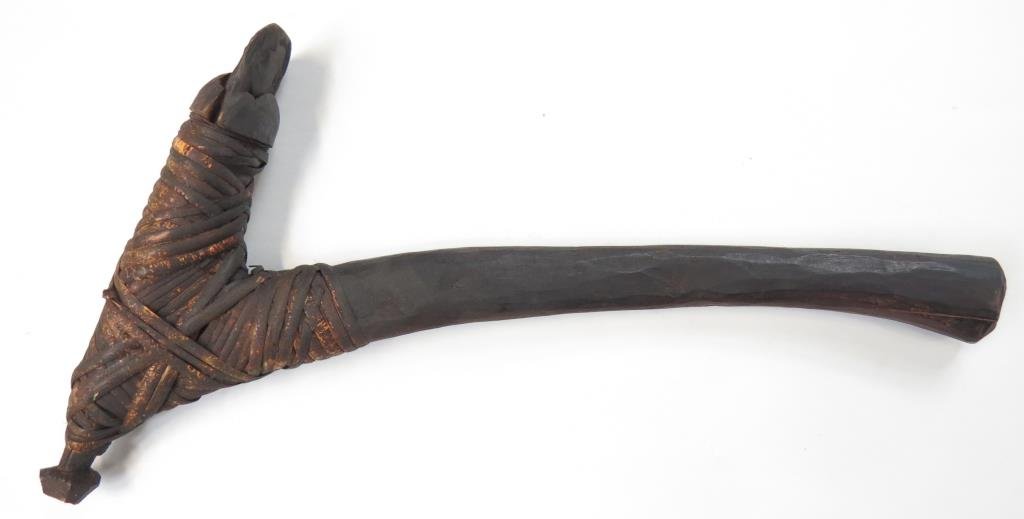 A RARE PAPUA NEW GUINEA ADZE: With lightly-curved wooden grip set perpendicular to the rattan-bound hardstone head with sharpened edge. Used as both weapon and tool. Good patina. Latter 19th century. Light wear. Overall length 41