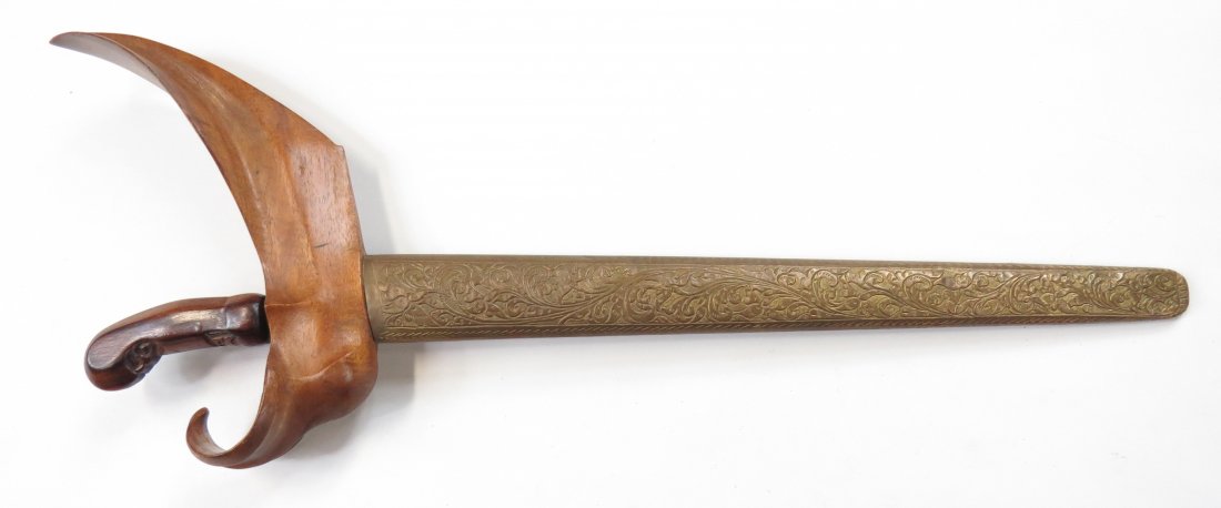 A BALINESE KRIS SWORD: The exotic hardwood grip with scrolled pommel, the waved, double-edged blade with two short fuller at the forte, forged of extremely fine pamor damascus steel. In its wooden scabbard with carved wrang