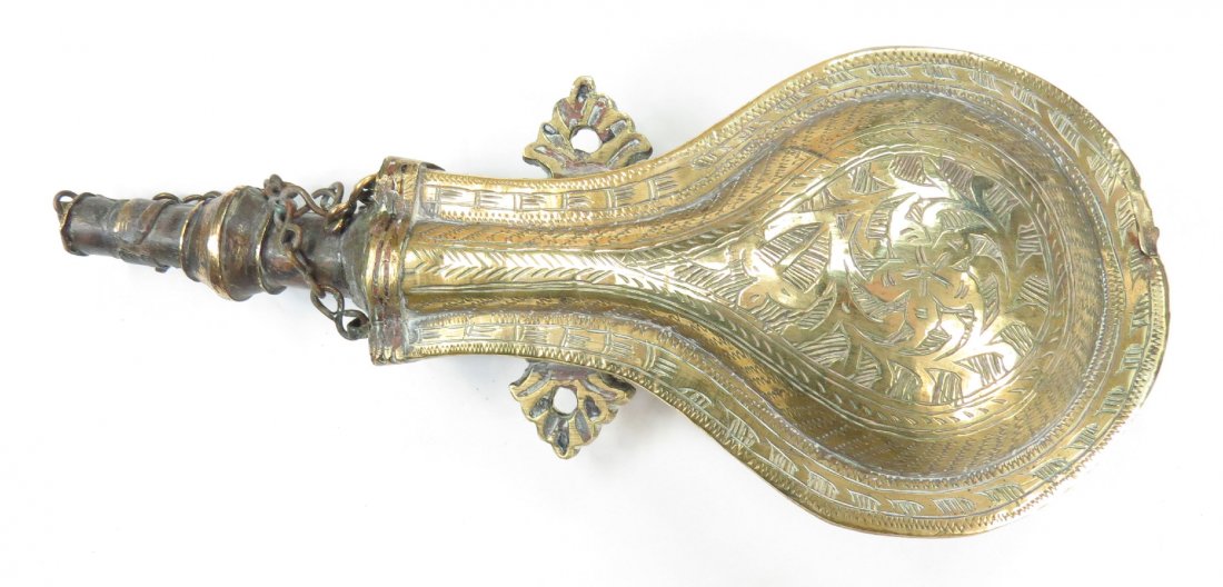 A MOROCCAN POWDER FLASK: Wrought of brass and well-engraved overall. Latter 19th century. Minor wear. Overall length 23.5cm. Condition II