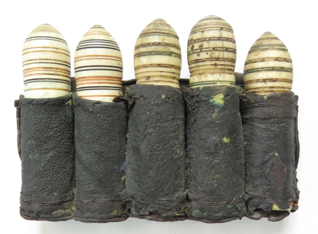 A RARE SET OF EASTERN EUROPEAN POWDER CHARGERS: Serbian or Southern Hungarian, each of five chargers turned of a single large section of antler, the domed terminals decorated with alternating colored bands. In their fitted leather case with remains