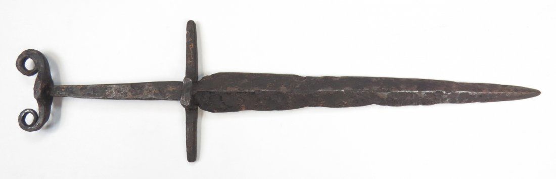 A MEDIEVAL DAGGER: Probably French. Wrought entirely of steel, with broad guard and pommel with curled terminals. The broad blade straight, double-edged and continuously tapering to an acute point. 14-15th century. As f