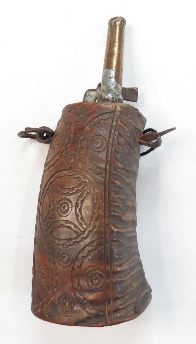 A MOROCCAN POWDERHORN: Carved of a single section of ramshorn, showing influence from the form of European horns of the 17th century. Carved with characteristic motifs, with brass mounts. Early 19th century. Worn. Overall h