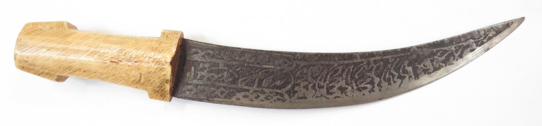 A SUDANESE DAGGER: The polished bone grip with flared pommel and bolsters, the curved, double-edged blade etched overall with Arabic calligraphy. Late 19th century. Minor wear. Overall length 25cm. Condition II