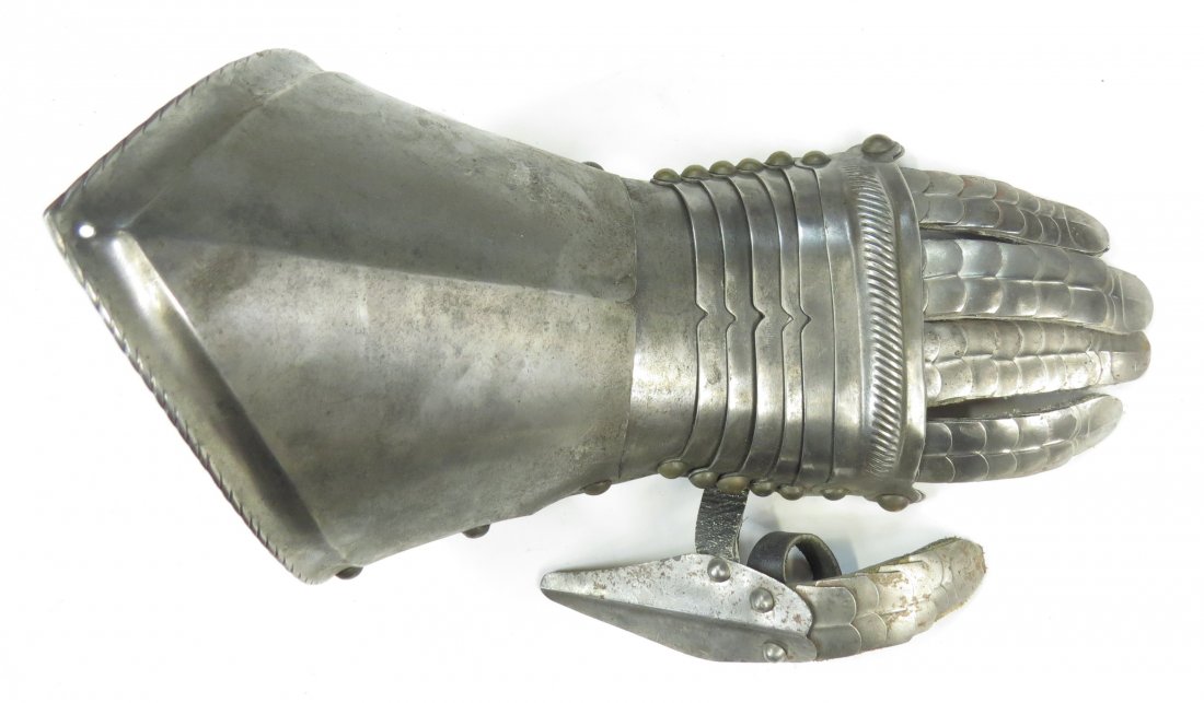 A VICTORIAN-ERA ARMOR GAUNTLET: For the left hand. Very well wrought, with individual fingers and thumb, and brass studs. Excellent detail throughout including embossed fingernails. Latter 19th century. Worn, areas of rust. Overall 