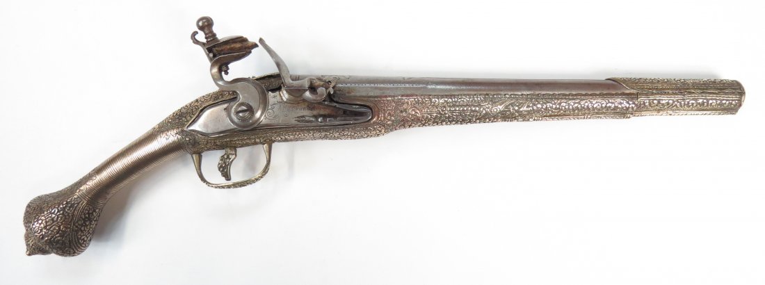 AN OTTOMAN KUBUR PISTOL: The stock wrought entirely of silver, embellished overall with baroque flowering vinework. The elegant flint mechanism engraved, the chiseled barrel struck with an Ottoman maker’s mark in gold, IBRA