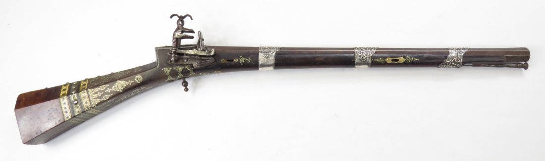 AN OTTOMAN SHISHANA RIFLE: Rare in carbine length, made for a horseman. The dark hardwood stock of characteristic form, with burlwood butt, and inlaid with brass studs, horn and bone in complex geometrical motifs. The miquelet 
