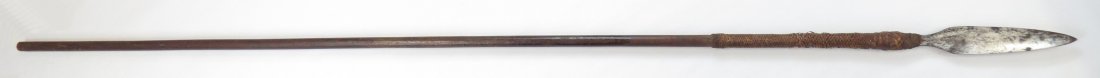 A RARE MORO SPEAR: The brad head of characteristic form. Retained in the well-patinated hardwood haft with plaited coir. Late 19th century. Well worn. Overall length 180.5cm. Condition III