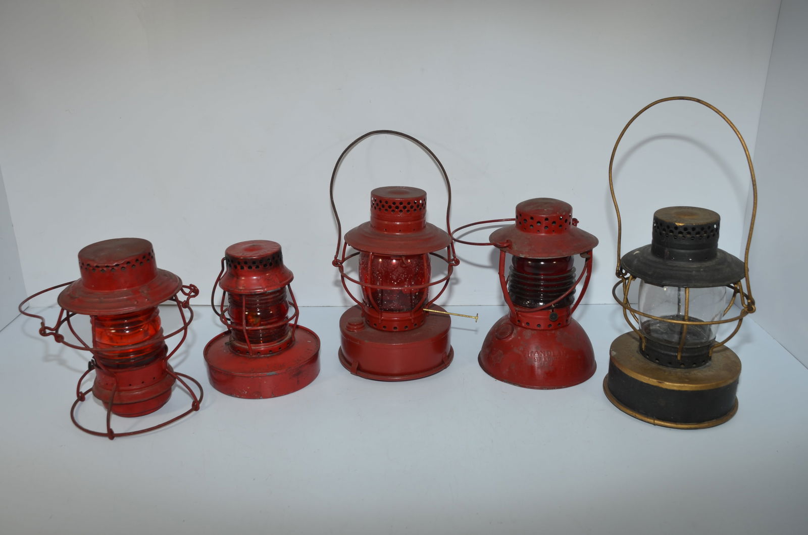 Five Mixed Handlan Lanterns: This is a lot of five mixed Handlan lanterns. The first has a red cast HANDLAN INC Fresnel globe, burner, and fount. The second has a red HANDLAN NO 57 Fresnel globe, burner, fount cap, and the fount