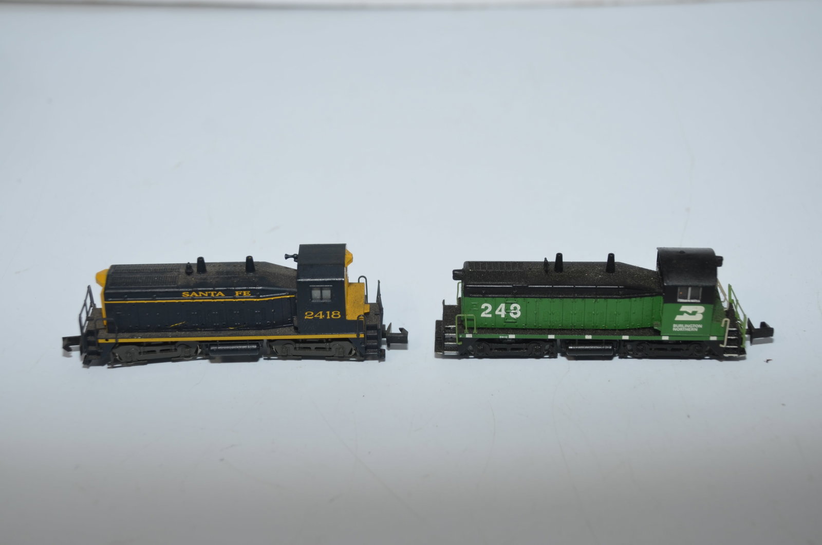 Two SW-1500 Diesel Locomotives-Santa Fe RR/Burlington Northern RR-N Scale: This is a pair of used SW-1500 diesel locomotives in N scale. Both have been tested and run well. The first is a Santa Fe Railroad loco #2418, made by Arnold, while the second is a Burlington Northern
