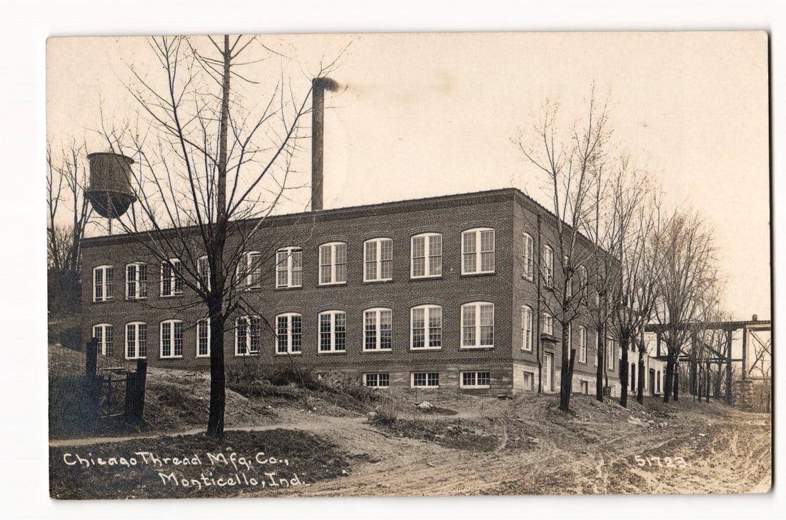 Chicago Thread Mfg. Co. Factory Building, Monticello, Indiana, Exterior View, circa 1912.: The postcard displays a sepia-toned photograph of an industrial building. The main subject is a two-story brick structure, identified by text as the Chicago Thread Mfg. Co. in Monticello, Indiana. Vie