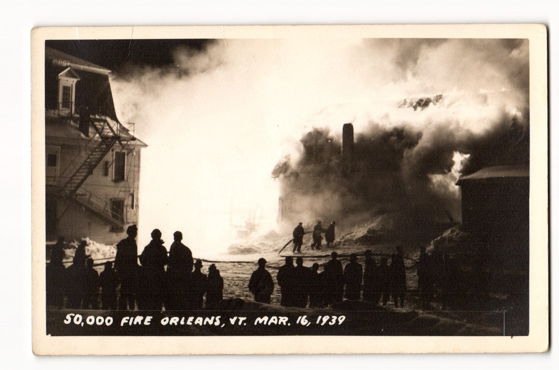 Orleans, Vermont, $50,000 Fire Scene, Night View with Spectators, March 16, 1939: The photograph on the front captures a harrowing nocturnal conflagration. The central visual element is a building, or possibly multiple adjacent structures, fully consumed by fire. Intense, bright li