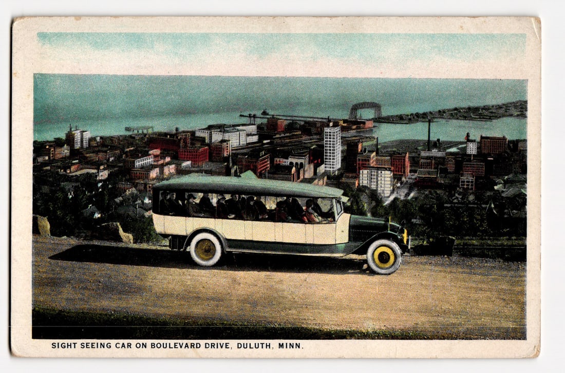 Sight Seeing Car on Boulevard Drive, Duluth, Minn., Overlooking City and Lake Superior: The front of the postcard depicts a colorized image of a antique sight-seeing car, cream and dark green, filled with passengers, traveling on a dirt road labeled "BOULEVARD DRIVE." The perspective is