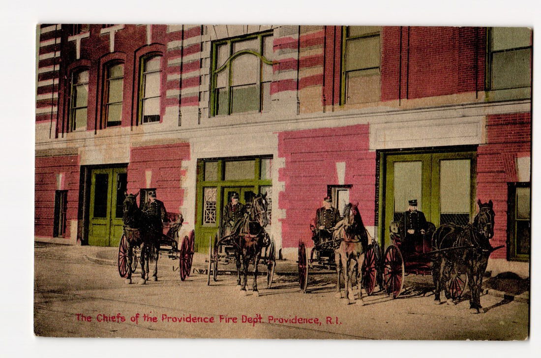 Providence Fire Department Chiefs with Horse-Drawn Carriages, Providence, R.I., ca. 1900s: The front of the postcard features a colorized photograph showing four horse-drawn carriages, each with a uniformed driver, arrayed in front of a multi-story brick building, likely a fire station. The