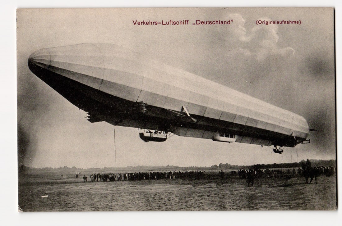 Verkehrs-Luftschiff „Deutschland?? in Flight, Crowd Below, circa 1910 Photograph Postcard: The front of the postcard features a sepia-toned photograph of the Verkehrs-Luftschiff „Deutschland”. The airship is depicted at a low angle, appearing to be either taking off or landing, with