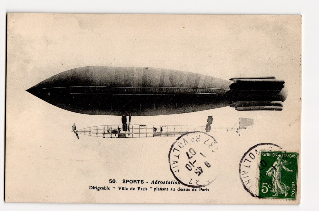 Aérostation Dirigeable "Ville de Paris" Soaring Above Paris, Early 20th Century Aviation: The front of the postcard features a photographic image of a large, dark-colored dirigible, presented in a side profile view. The dirigible has an elongated, somewhat cigar-shaped body with distinct t