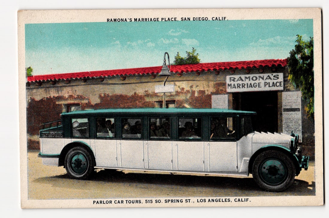 Ramona's Marriage Place, San Diego, Calif. with Parlor Car Tours Bus, Los Angeles Advertising: The front of the postcard features a colorized image of a long, multi-windowed passenger bus, predominantly white with green trim and roof. The bus is parked in front of a single-story building with a