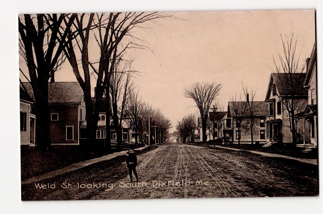 Weld St. Looking South, Dixfield, Maine. Early 20th Century Residential Street View with Figure.: The front of the postcard features a sepia-toned photograph depicting a perspective view looking south down Weld Street in Dixfield, Maine. The unpaved street, marked with wheel ruts, recedes into the