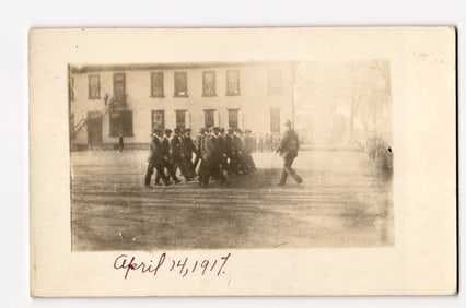Real Photo Postcard of Men Marching, Building Behind, Collinsville, Conn. Dated April 14, 1917