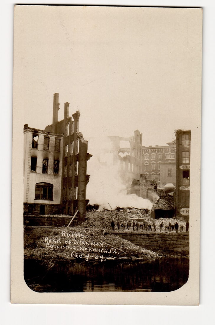 RPPC Postcard: Ruins of Shannon Building from Rear, Norwich, CT, After Fire, Feb. 9, 1904: This Real Photo Postcard (RPPC) presents a sepia-toned photographic image of the aftermath of a fire. The primary subject is the heavily damaged, multi-story brick structure identified by handwritten