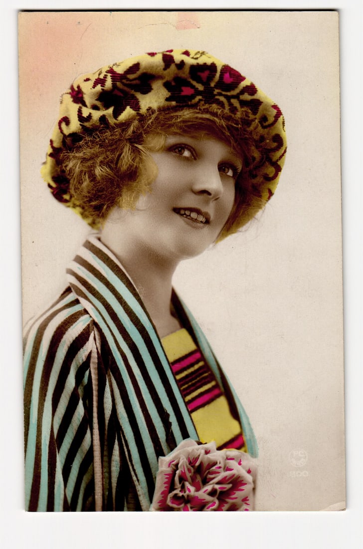 Woman in Patterned Hat & Striped Jacket, Hand-Tinted Photo Postcard, P-C Paris, France: A hand-tinted photographic postcard depicting a woman from the chest up, angled slightly to her left, with her gaze directed upwards and to her right. She has short, curly, light brown or reddish hair