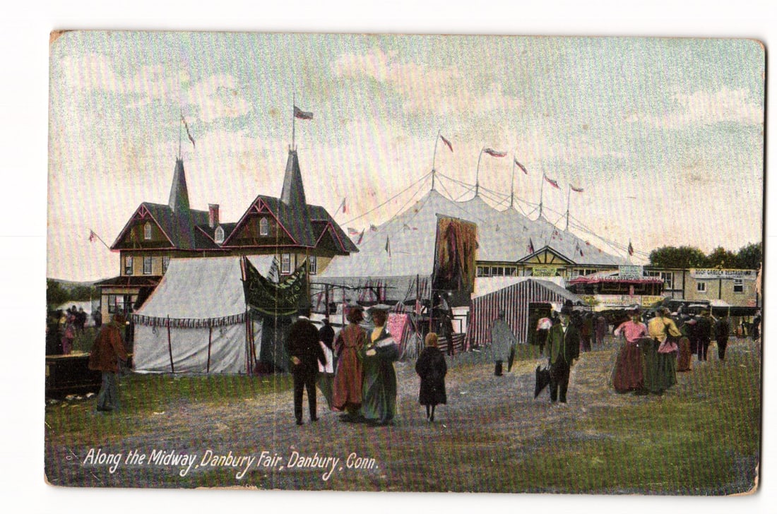 Danbury Fair Midway with Tents and Attendees, Danbury, Conn. circa 1907 color postcard.: A colorized print depicting numerous people, dressed in early 20th-century attire, strolling along a dirt path at a fair. In the midground, several tents are visible, including a large, multi-peaked c