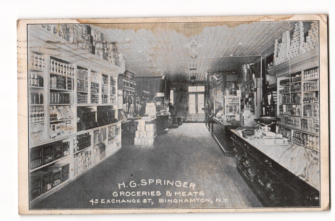 Antique Postcard: H.G. Springer Groceries & Meats Interior, Binghamton, NY, 1917 Postmark.: The front of the postcard features a black and white, possibly sepia-toned, photograph of the interior of a grocery and meat store. The perspective is from the entrance, looking down a central aisle t