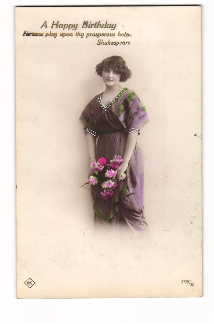"A Happy Birthday" postcard: Woman in early 20th C. dress with flowers, Shakespeare quote.: A full-length portrait of a woman standing, facing slightly to her right, looking towards the viewer. She holds a bouquet of pink and fuchsia flowers with green foliage in both hands, positioned low a