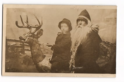 Sepia Real Photo Postcard: Santa Claus with Child and Reindeer in Studio Portrait, circa 1900s.