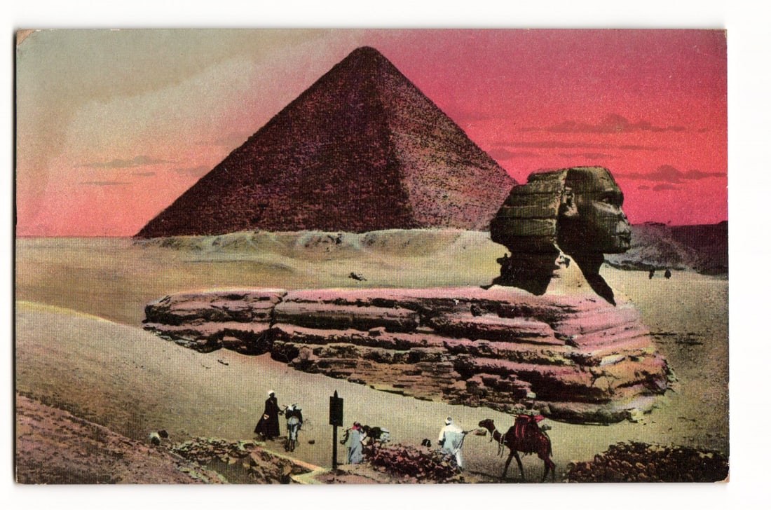 Egypt Postcard: The Great Sphinx and Pyramid of Cheops at Giza with Figures and Camels.: A color-tinted photograph or photolithograph depicts the Great Sphinx in the right foreground, viewed in profile facing right, with the Pyramid of Cheops (identified on the reverse) rising prominently