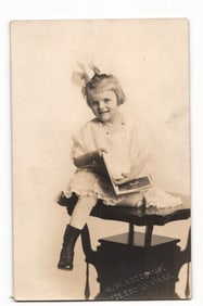 RPPC Young Girl with Large Bow, Holding Book, Seated on Table, Attleboro, Mass. Postcard