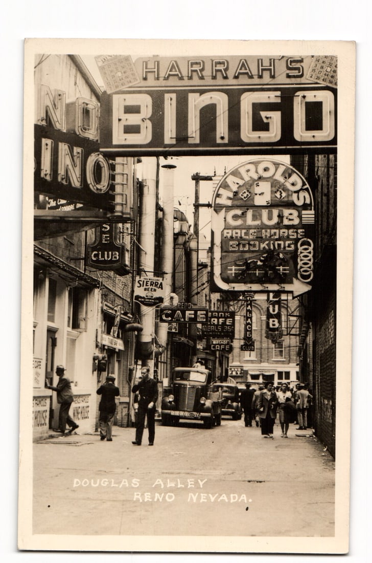 Reno, Nevada, Douglas Alley with Harrah's Bingo & Harold's Club Signs, 1949 RPPC Postcard: A street-level photographic view of Douglas Alley in Reno, Nevada. The alley is lined with buildings featuring prominent illuminated signs. Centered at the top is a large "HARRAH'S BINGO" sign. To its