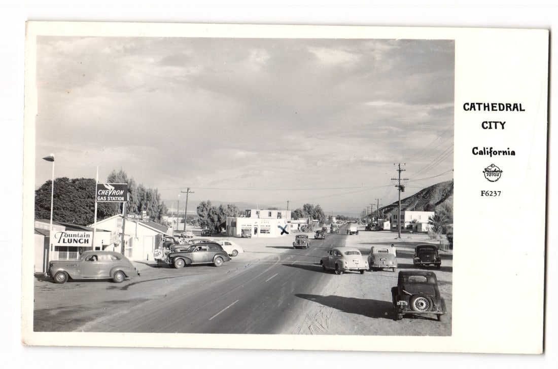 Postcard: Cathedral City, California Street View, Chevron Station, c. 1940s-50s Automobiles: Real Photo Postcard (RPPC). Black and white image, Cathedral City, California street. Circa 1940s-1950s automobiles are on a paved road. Signs visible include "Fountain LUNCH" and "CHEVRON GAS STATION