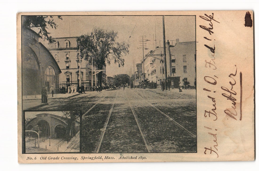 Springfield, Mass. Postcard: Old Grade Crossing Abolished 1890, Street View with Arch Inset: The primary image on this printed photographic reproduction postcard depicts a street scene in Springfield, Mass. The perspective looks down a cobblestone road featuring parallel tram tracks that rece
