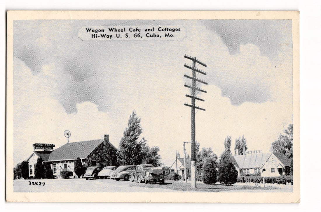 Wagon Wheel Cafe & Cottages, Hi-Way U.S. 66, Cuba, Mo. Vintage Roadside Scene Postcard: A black and white or sepia-toned image depicts the Wagon Wheel Cafe and Cottages. On the left, a stone-faced building with a gabled roof features a sign "FINE FOOD / WAGON WHEEL". Several automobiles,