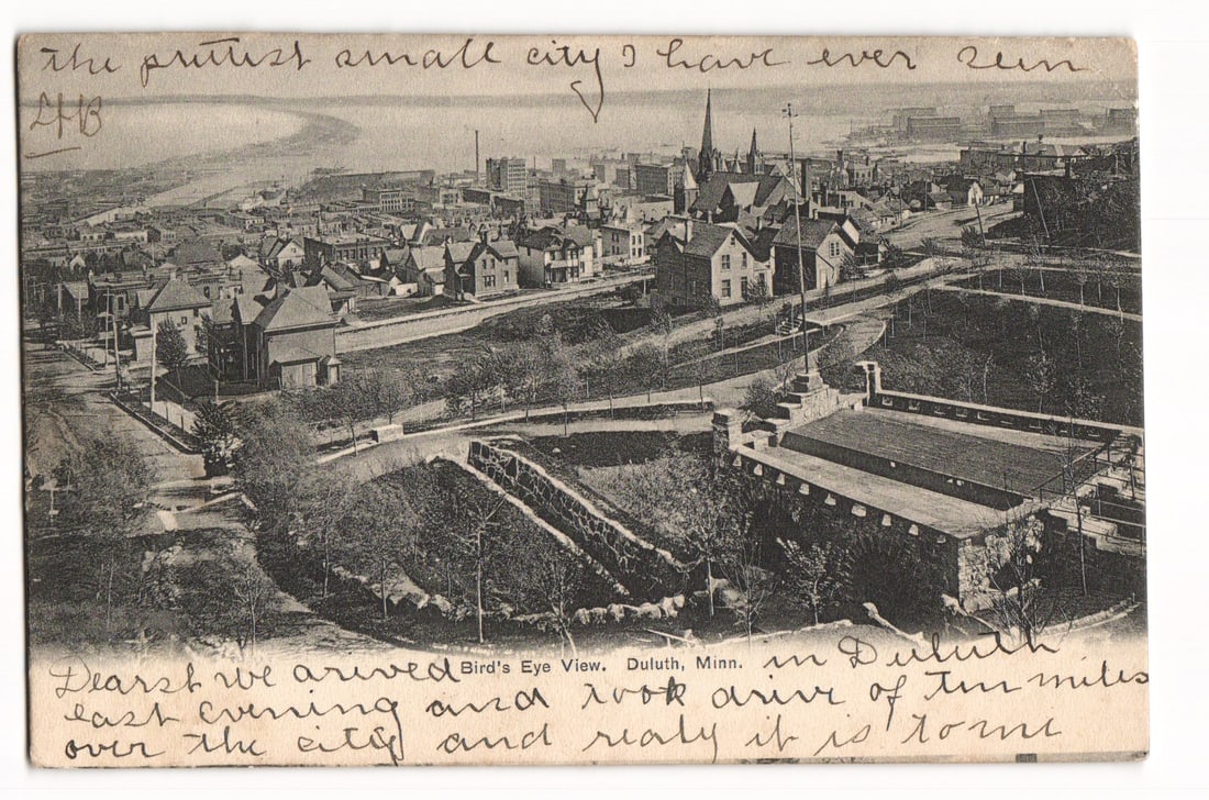 Bird's Eye View of Duluth, Minn. Cityscape Postcard, Postmarked Houghton, Mich. 1906: A sepia-toned photographic print postcard presenting a high-angle, bird's-eye view of Duluth, Minnesota. The image captures a sprawling cityscape with numerous residential and commercial buildings, in