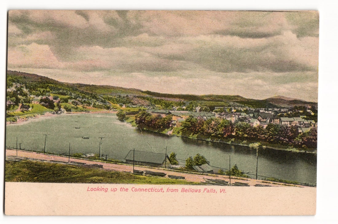 Scenic View Up the Connecticut River from Bellows Falls, Vermont; Vintage Color Postcard: A colorized print depicting an elevated, panoramic view looking up the Connecticut River from Bellows Falls, Vermont. The river occupies the central portion of the image, with several small boats visi