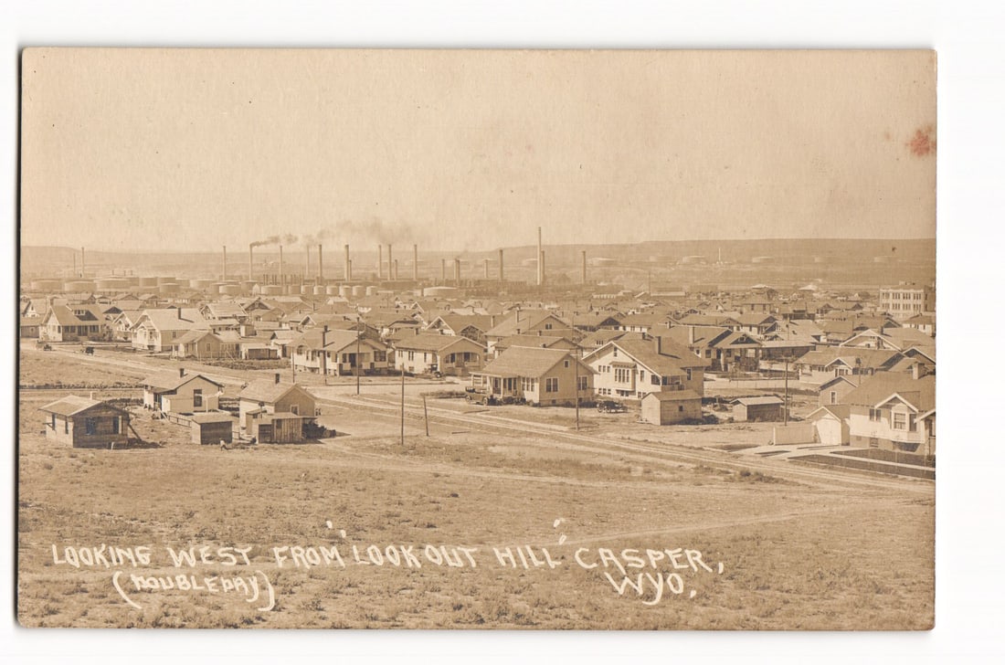 Casper, Wyoming: Westerly View from Look Out Hill (Doubleday) with Industrial Complex Postcard: A high-angle photographic view looking west from Look Out Hill over Casper, Wyoming. The composition shows a residential area in the foreground with numerous houses of various architectural styles and