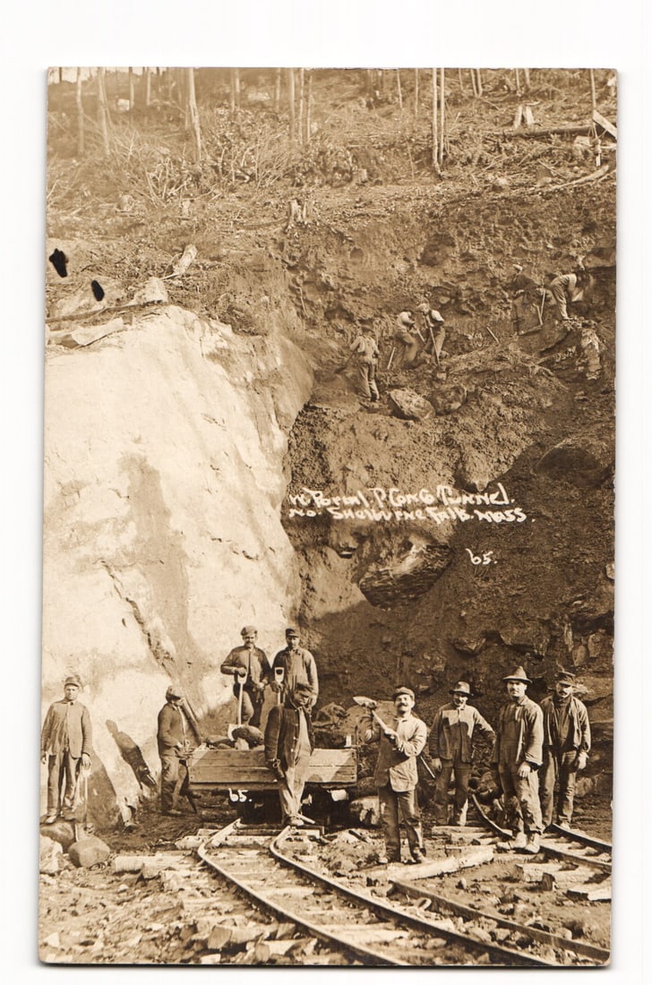 RPPC Hoosac Tunnel No. Shorevfine Sta. Mass. Workers & Rail Cart, circa 1904-1918 Postcard: A sepia-toned Real Photo Postcard (RPPC) depicting a group of at least twelve men, likely workers, at an excavation site. In the foreground, approximately seven men stand or are posed near a small rai