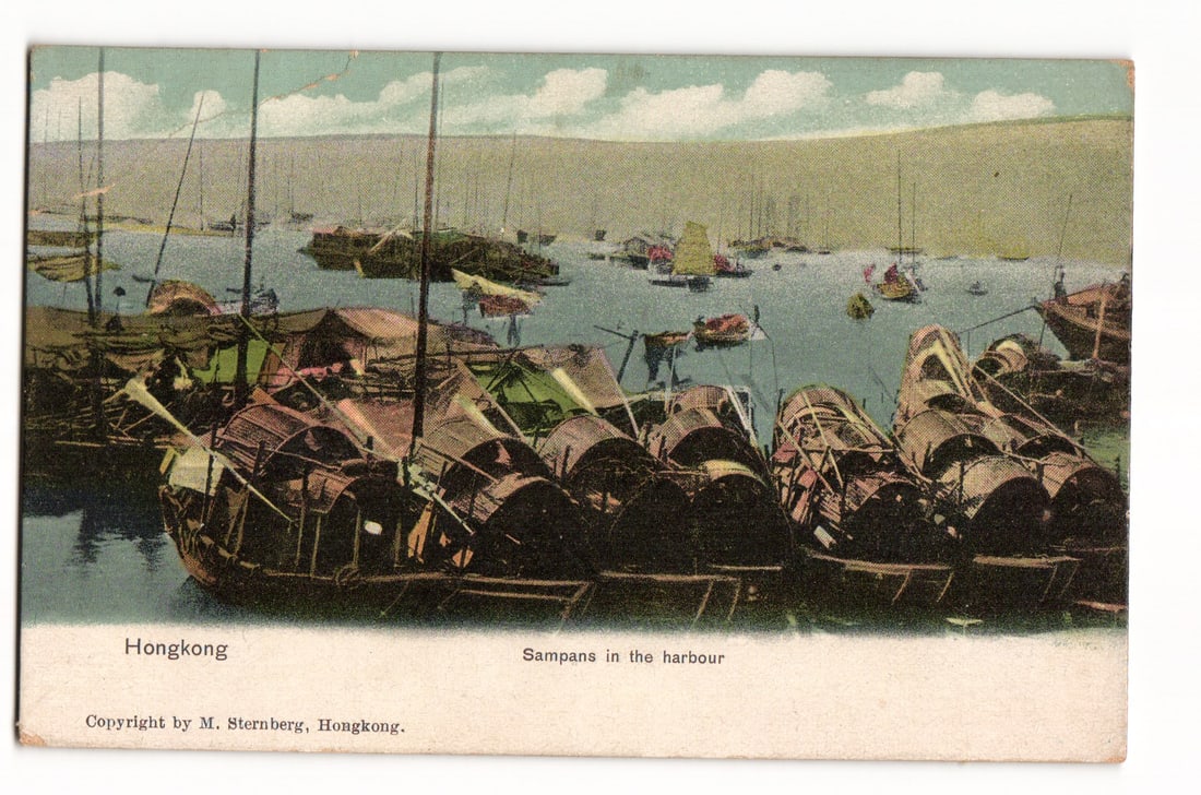 Hongkong postcard: Sampans in the harbour, numerous boats with barrel-like structures on water: A color image depicts numerous boats, identified as sampans, in a harbor setting. In the foreground, several large sampans are prominent, featuring distinctive dark, barrel-like or cylindrical superst