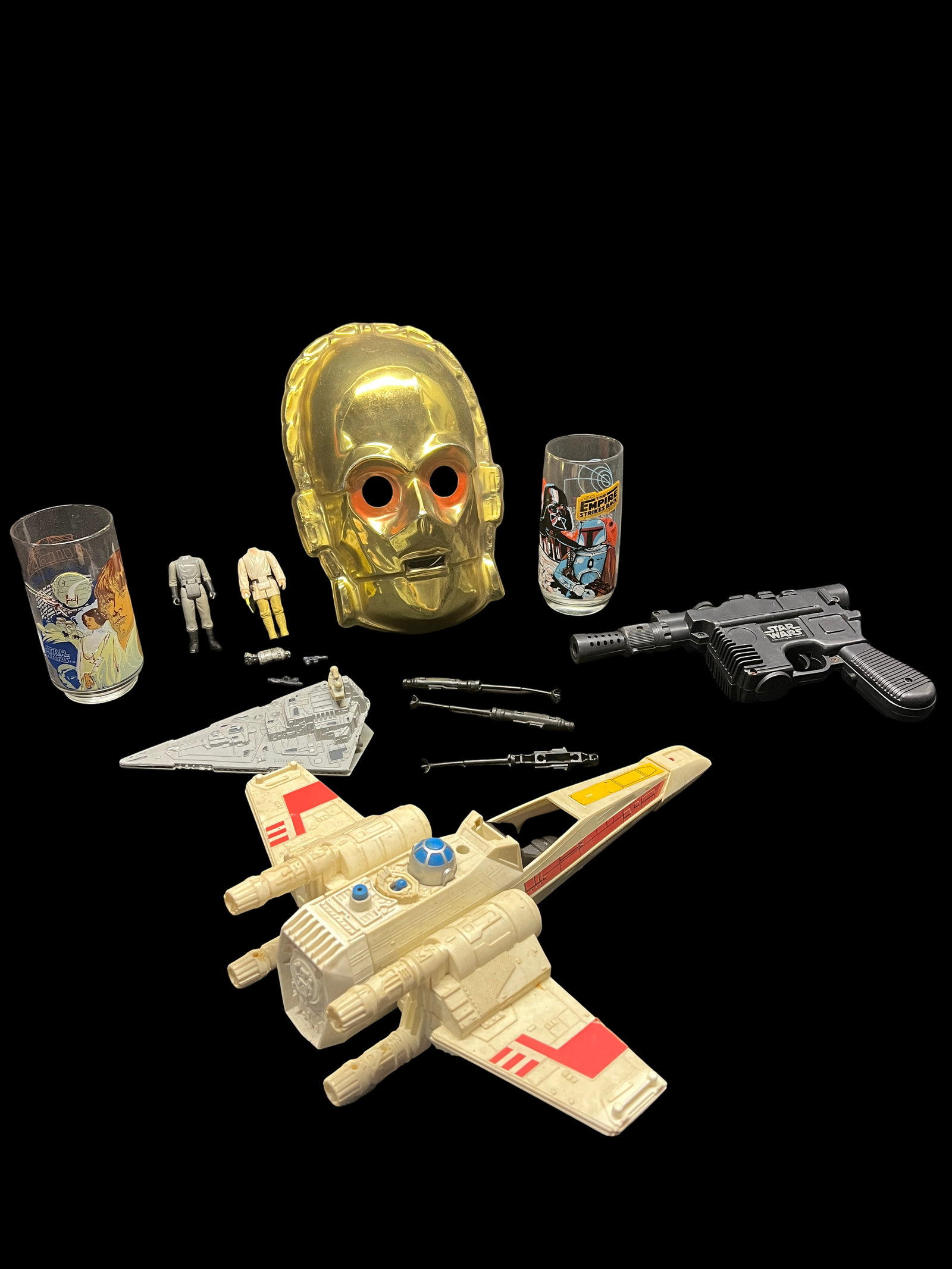 Vintage Lot of Star Wars Toys: C-3PO Mask, Glasses, Blaster & More: A mixed collection of classic Star Wars playthings centering on a chrome-yellow C-3PO face mask with original elastic strap and $1.29 price tag still attached, accompanied by two Burger King promotion