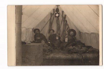 RPPC Postcard of Three US Army Soldiers in Camp Tent with Guidon, Stacked Rifles & Liquor c. 1910