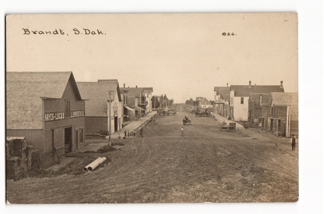 RPPC Real Photo Postcard of Main Street in Brandt, South Dakota. Hayes-Lucas Lumber Co. c. 1910s.: Please view photos for further description and condition considerations. Please know the scans may be darker or lighter than the actual card's true appearance. ACME Auctions offers FREE DOMESTIC SHIPP