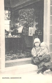 Postcard of two children in traditional Dutch costume sitting in a doorway, Isle of Marken, c. 1911