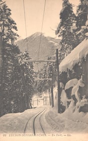 Postcard view of the Luchon-Superbagnères funicular railway track through the snowy forest, France.