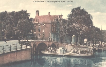 Postcard of Amsterdam showing the corner of Prinsengracht and Amstel canals with a bridge and barge.